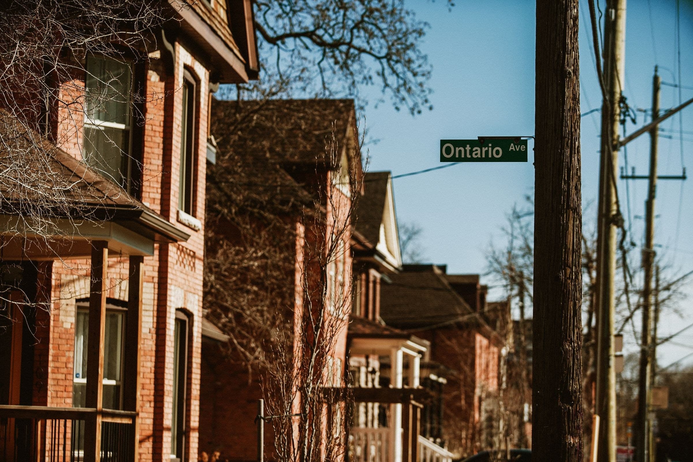 Row of older red brick houses with porches on a sunny street