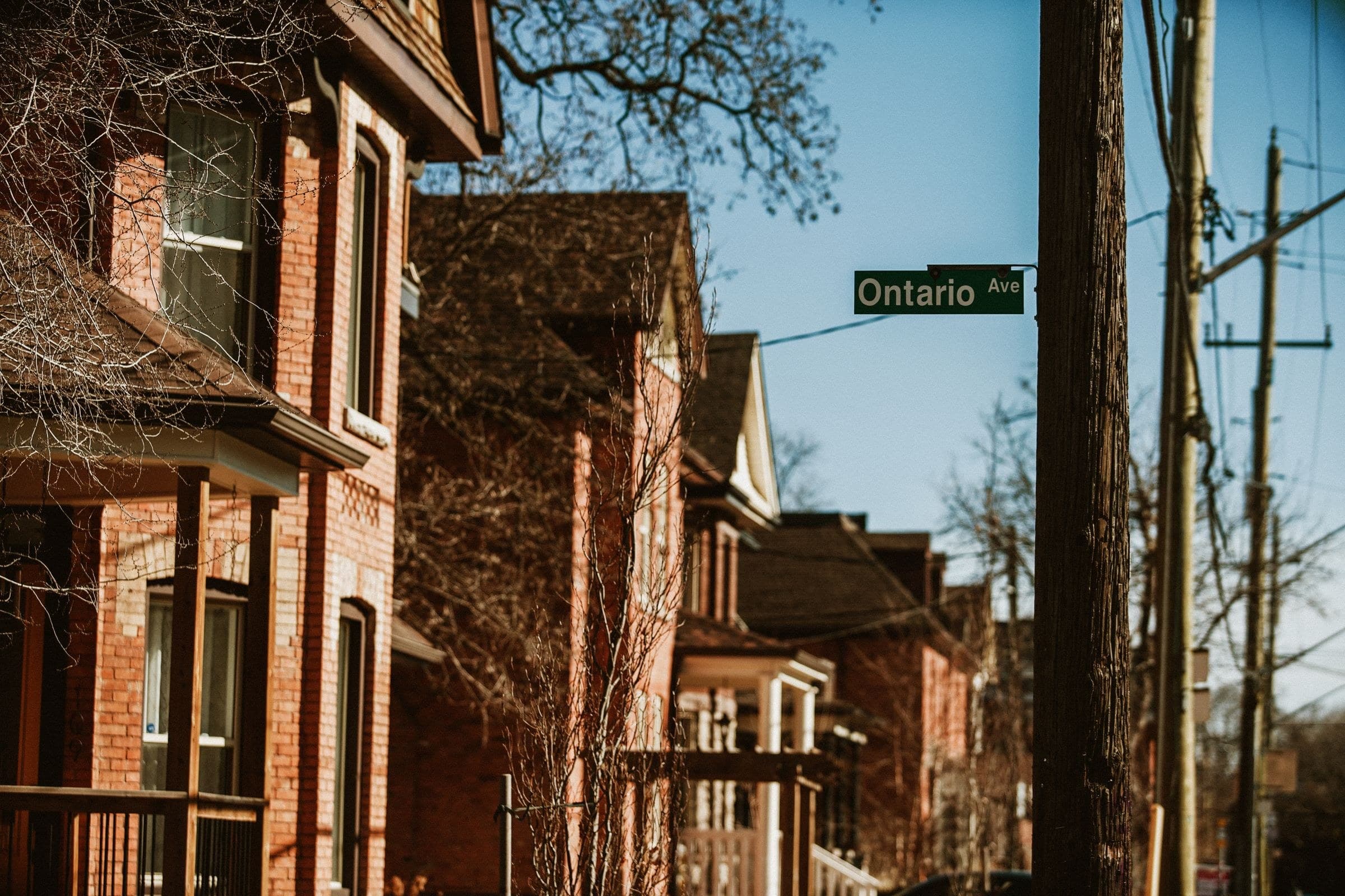 Row of older red brick houses with porches on a sunny street