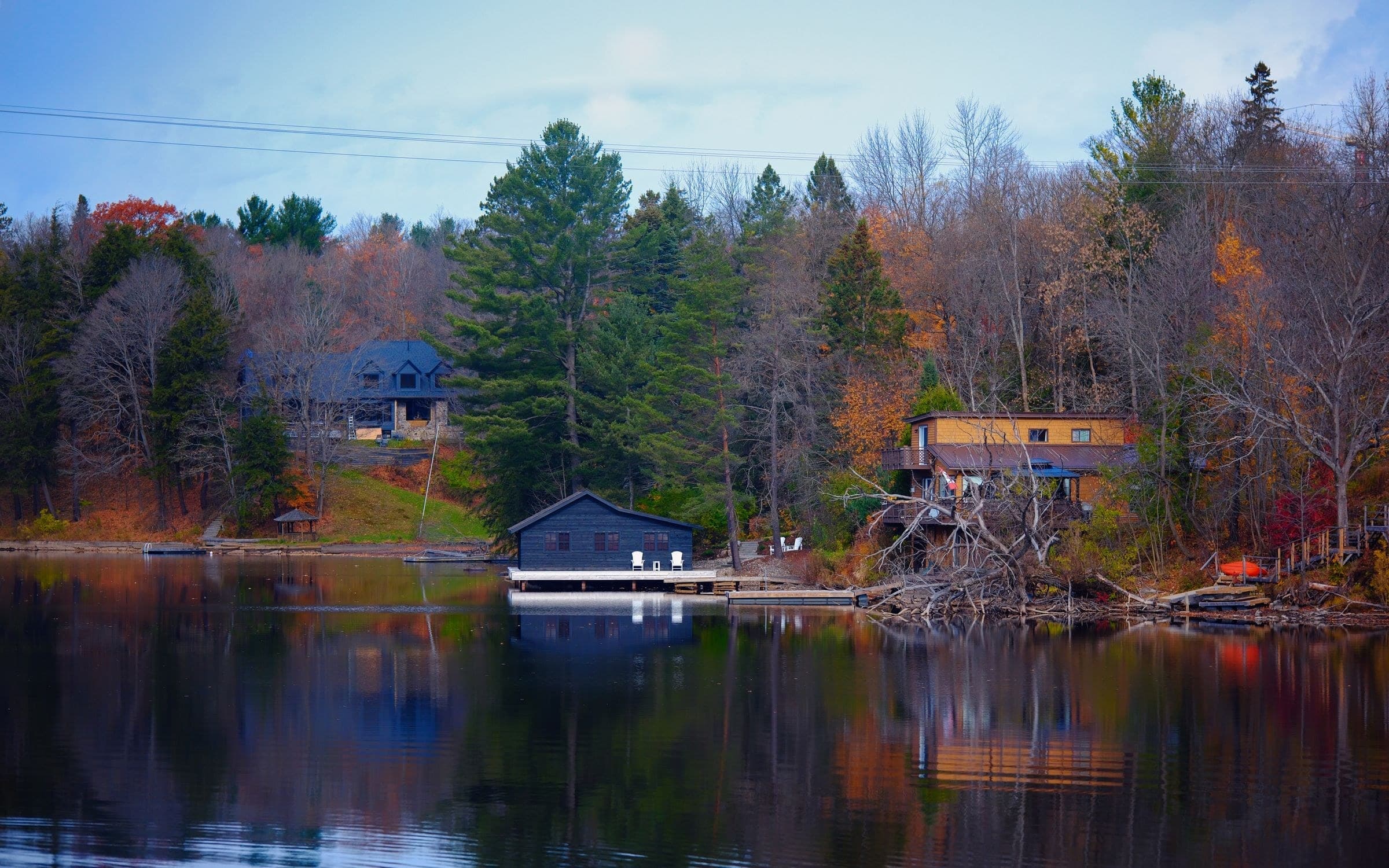 Wooded lakeshore with a boathouse and homes in fall colours