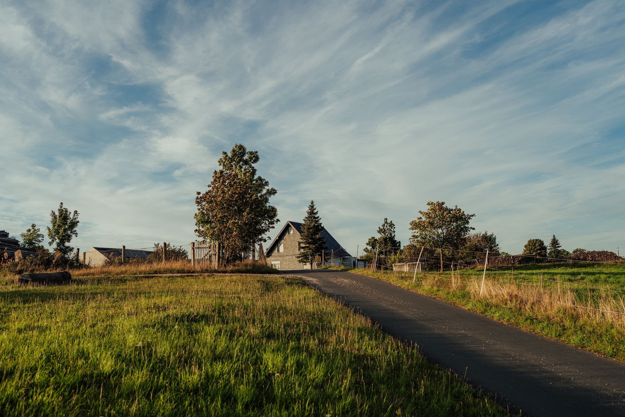 Country lane leading to a farmhouse under a big sky