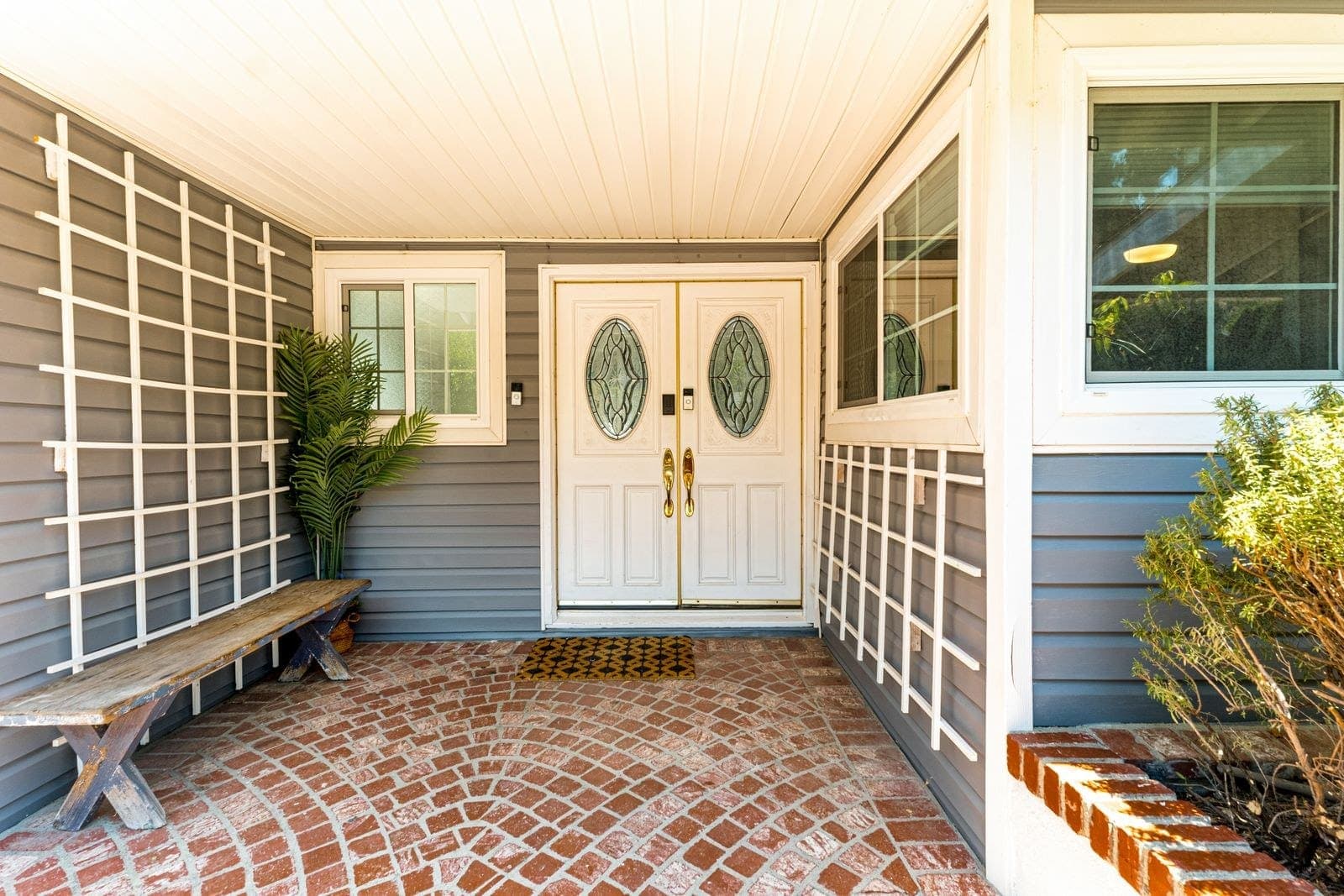 Covered entry with white double doors and leaded oval glass
