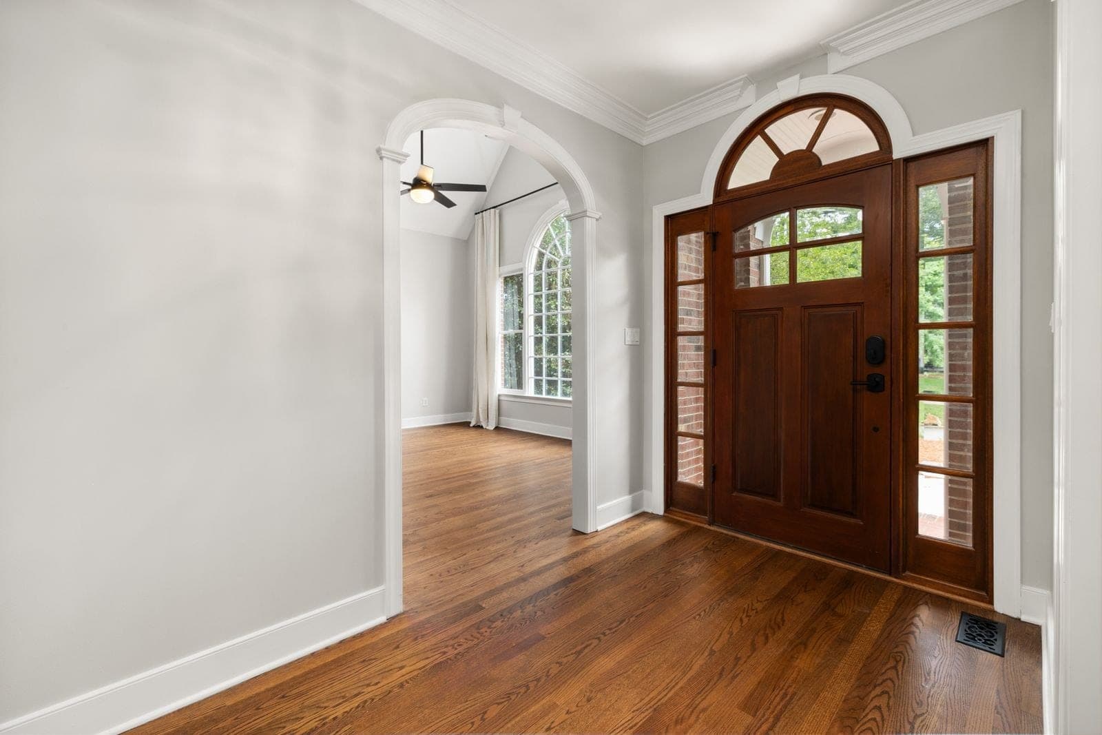 Wood entry door with sidelites and an arched transom inside a front hall