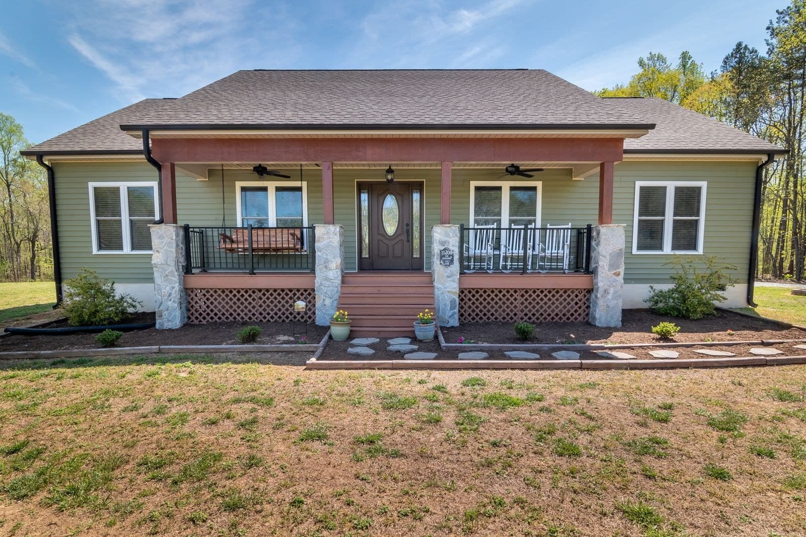 Green sided bungalow with a covered front porch and an oval-glass door