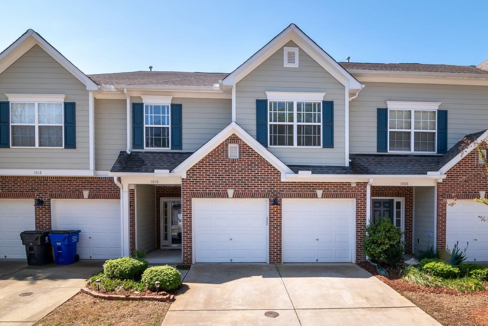 Brick and siding townhouses with white windows and single garages