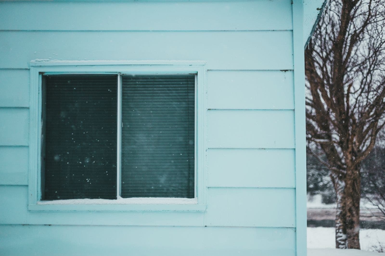 Two-pane window in mint siding during a snowfall