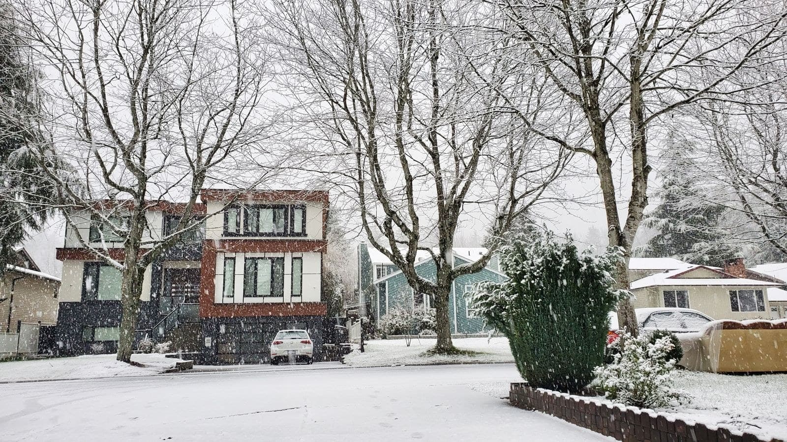 Suburban street of two-storey houses in falling snow