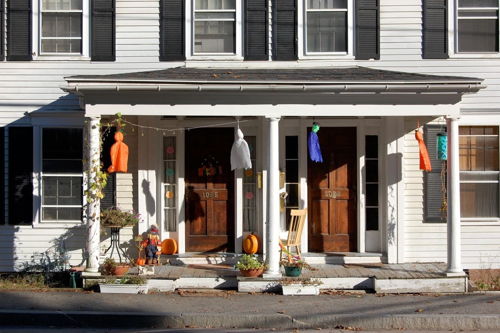 Old white clapboard house with a pair of wood front doors under a porch