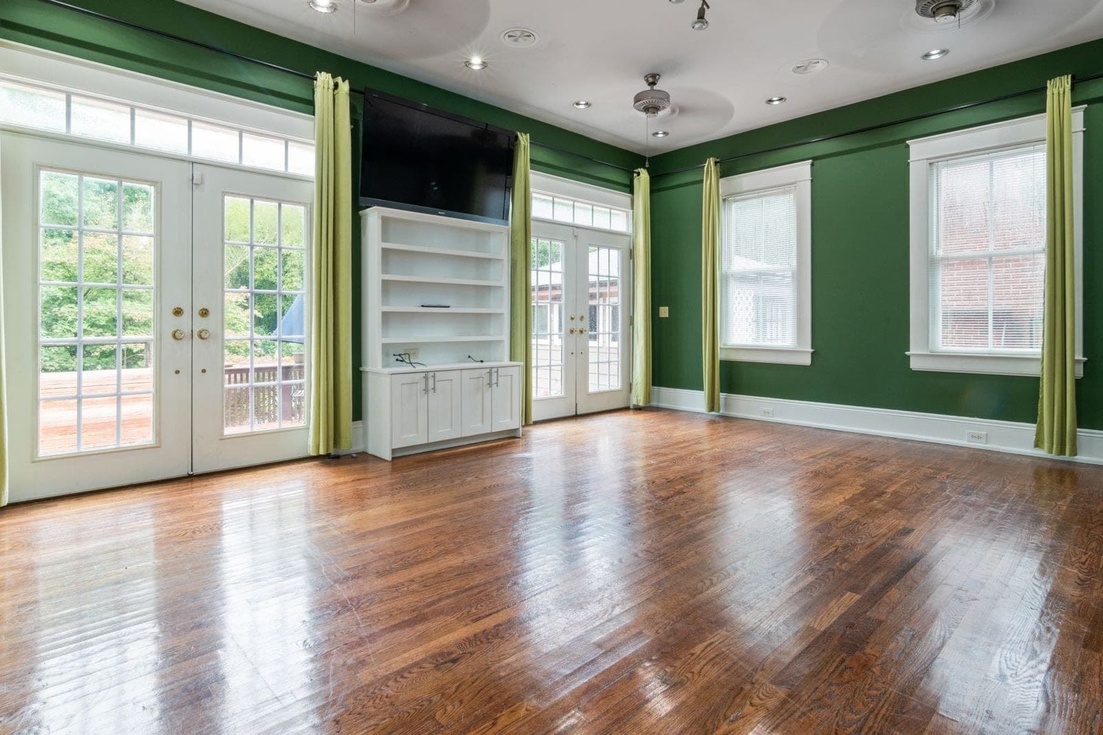 Room with green walls and two sets of glass garden doors with transoms