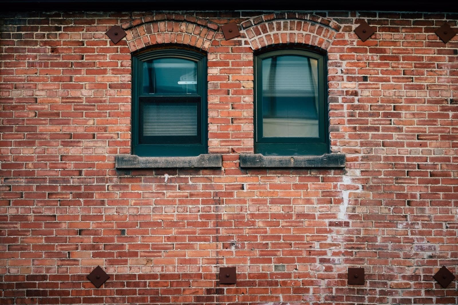 Two arched windows set in an old red brick wall