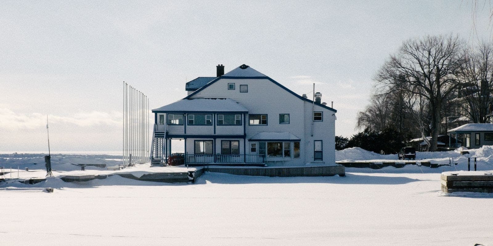 Large white house by a frozen shoreline in winter
