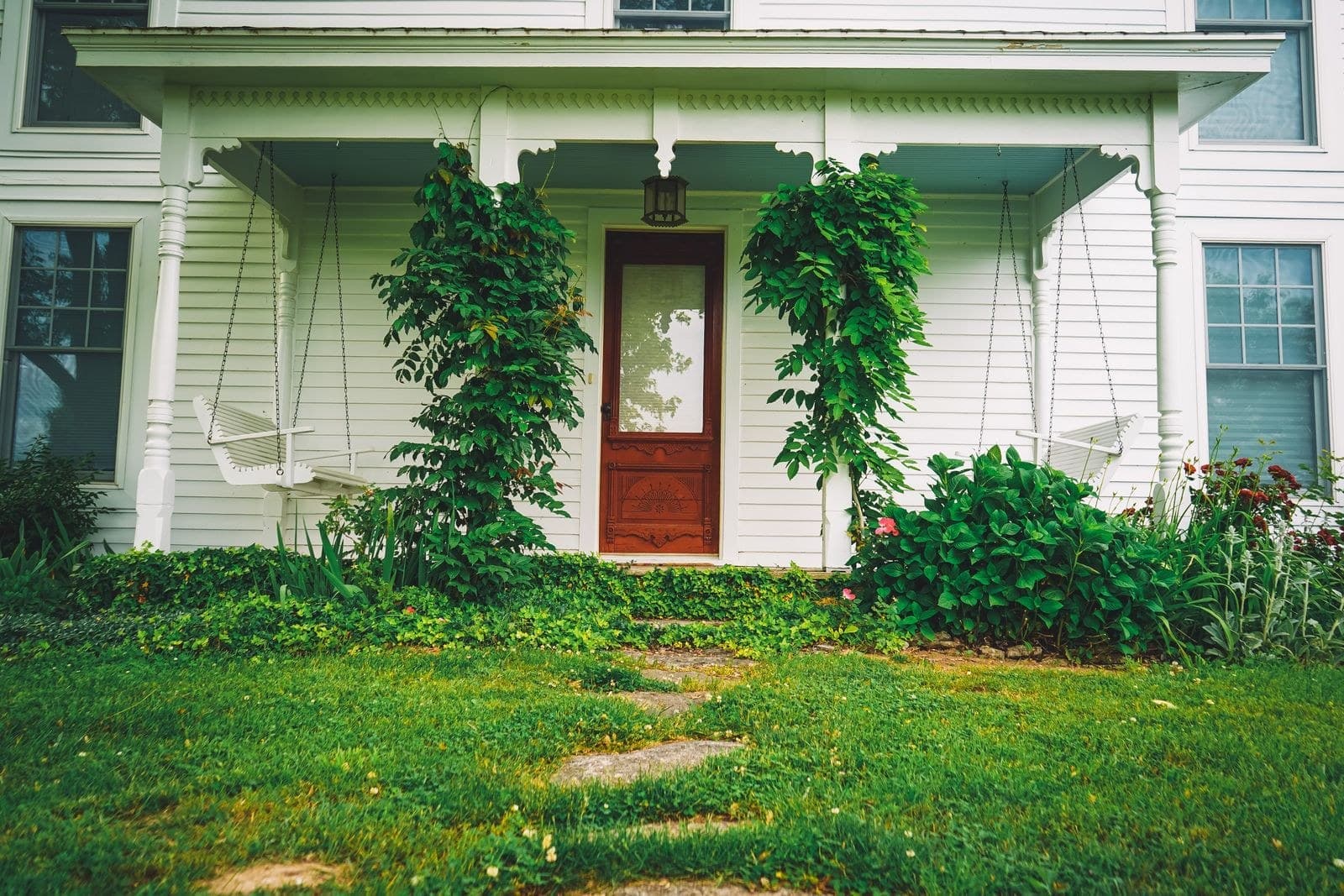 White farmhouse porch with a wood door and old double hung windows