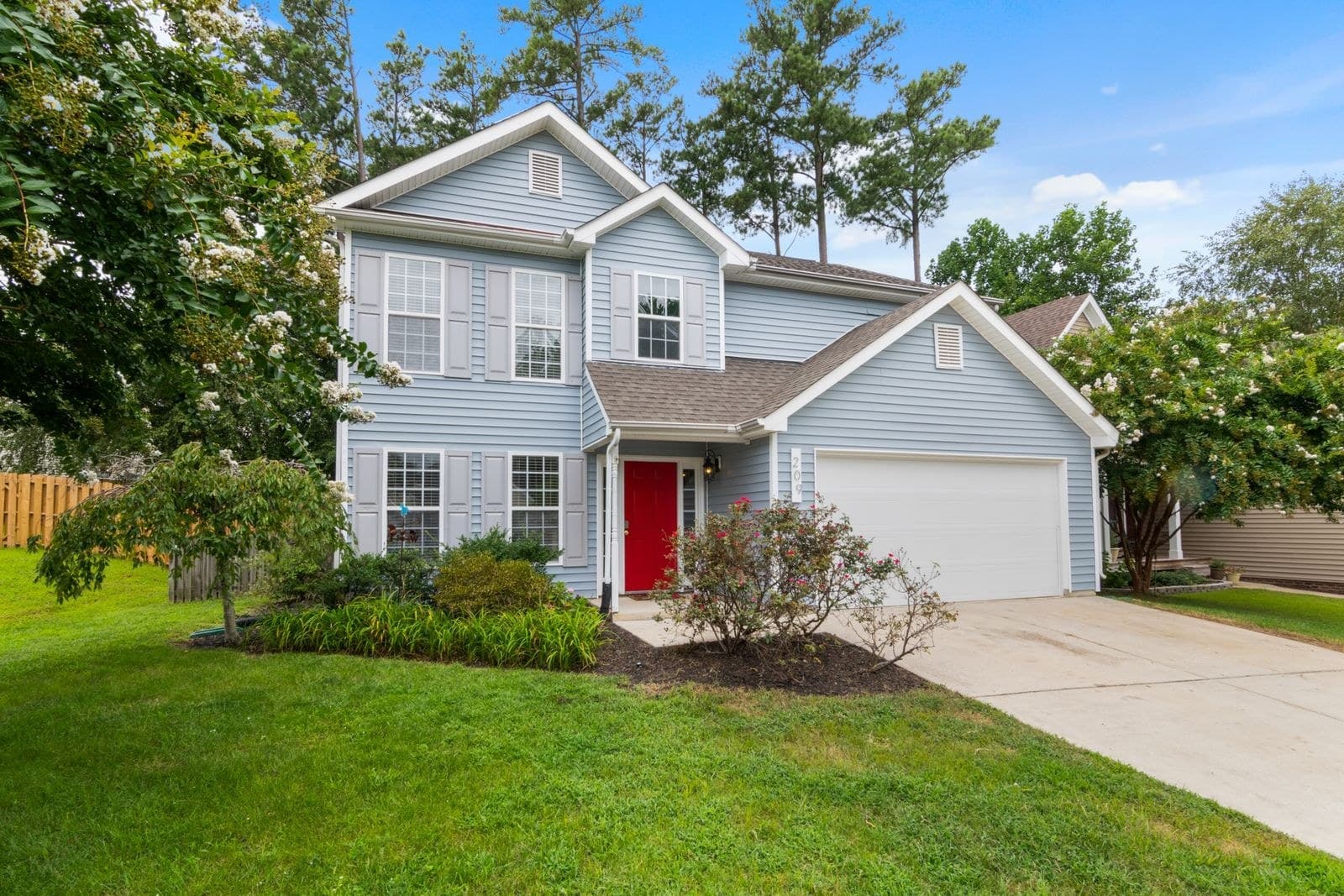Blue sided two-storey with a red front door and an attached garage