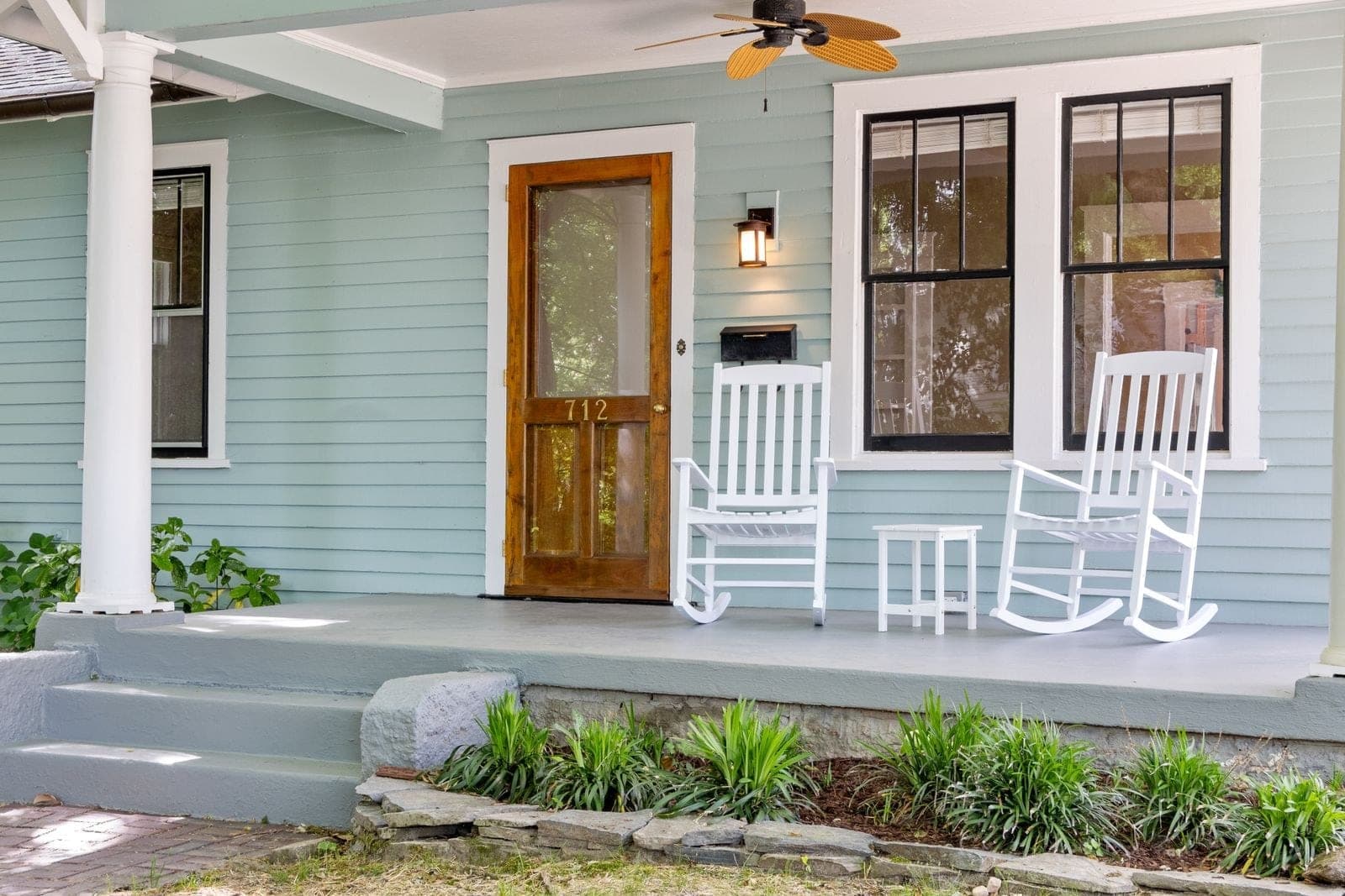 Porch with a wood front door, black-framed windows and white rockers