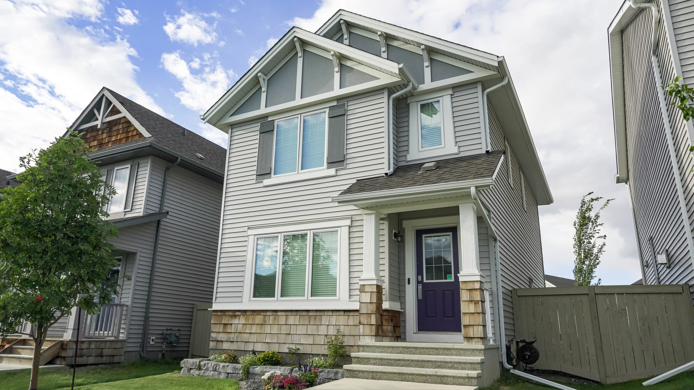 Two-storey house with a white vinyl window in every opening on grey siding